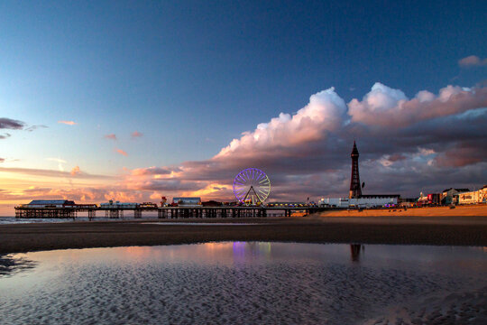 Blackpool Tower, Pier, illuminations and Amusements glowing in the evening light all reflected in the wet sands of the beach