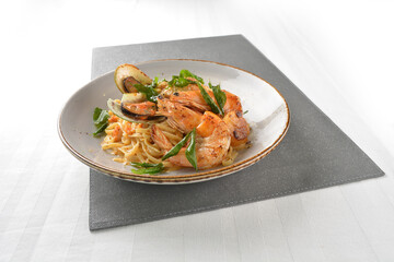 seafood pasta with big tiger prawn, scallop shell clam and muscle in olive oil salted egg yolk paste sauce in plate on white marble table western spaghetti cuisine halal food hotel luxury cafe  menu