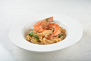 seafood pasta with big tiger prawn, scallop shell clam and muscle in olive oil salted egg yolk paste sauce in plate on white marble table western spaghetti cuisine halal food hotel luxury cafe  menu