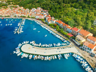 Aerial view of boats and luxury yachts, buildings at summer sunrise. Beautiful city Baska, Krk island, Croatia. Colorful landscape with sailboats and motorboats, architecture, sea bay, jetty. Top view