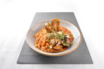 seafood pasta with big tiger prawn, scallop shell clam and muscle in spicy chilli crab tomato paste sauce in plate on white marble table western spaghetti cuisine halal food hotel luxury cafe menu