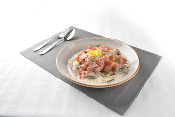 carbonara pasta noodle with bacon, ham and half boiled egg in creamy cheese white milk sauce in plate on white marble table western spaghetti cuisine halal food hotel luxury cafe menu
