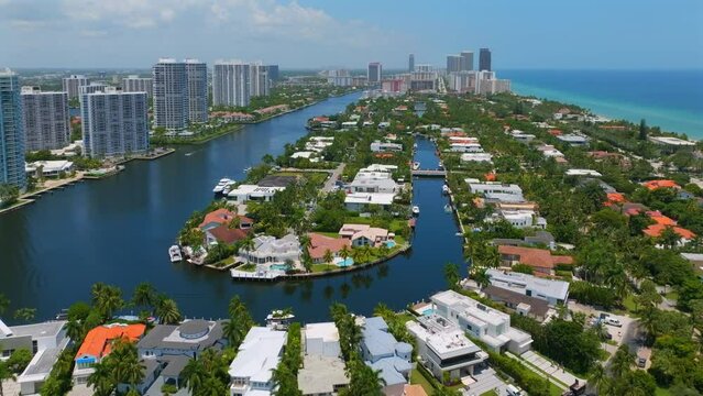 Aerial view of marvelous villas drowning in greenery with luxurious private yachts along channel in Golden Beach. Great look at high-rise buildings on other side of strait
