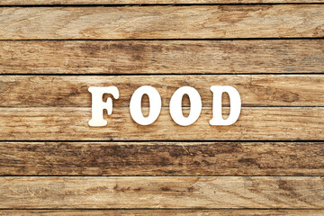 The word Food written on wood letters on wooden background, top view.