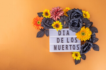 Dia de los muertos Feast flat lay, Mexican Day of the Dead holiday background with fall black, orange, yellow flowers, lightbox with text Dia de los muertos, colorful painted skull