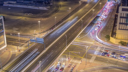 Top aerial view of busy road intersection and traffic junctions in Dubai city night timelapse.