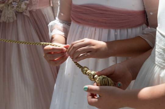 Vista de tres niñas vestidas de primera comunión que sujetan una cuerda en sus manos.
