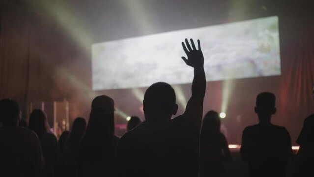 Hands of a crowd of people at a Christian meeting during the glorification of God, worship night at church, hands lifted up, guy raising hands up, praising the Lord, christian concert festival 