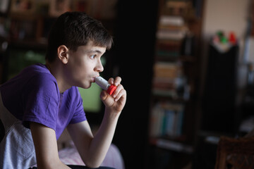 A teenage boy uses an allergy and asthma inhaler