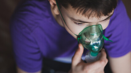 A teenage boy uses an allergy and asthma inhaler