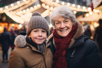 Portrait of a happy smiling grandmother and grandson in winter clothes at Christmas market.

