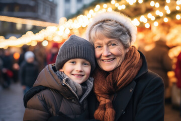Portrait of a happy smiling grandmother and grandson in winter clothes at Christmas market.

