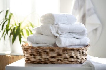 Fototapeta na wymiar Wicker baskets with clean white towels on white counter top table with beautiful morning sunlight 