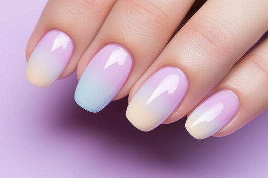 Woman's fingernails with gradient pastel colored violet, blue and yellow nail polish