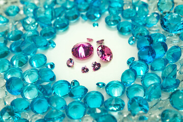 .A group of pink diamonds arranged in the middle of blue diamonds in a white background..Top view of pink diamonds. white gems background video 4K..Pink diamonds in heart shape and different size