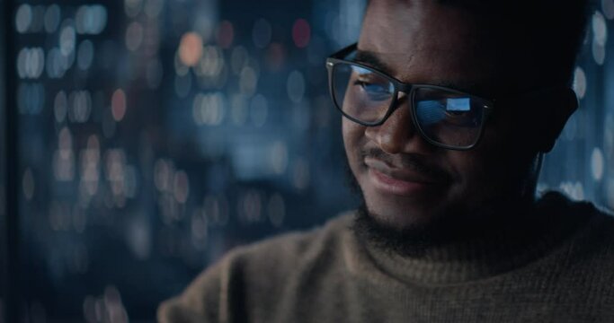 Close Up Portrait Of Successful Handsome Black Businessman Working on Laptop Late Night in Big City Office. Investment Manager Checking Financial Data from Project Management Report.