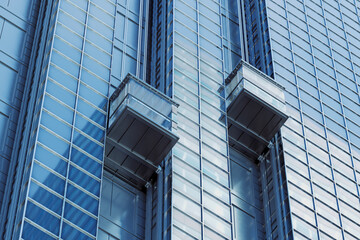 Two external elevators going up along a tall skyscraper. Reflective glass facade