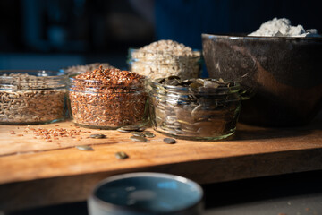 Cereals grains and pumpkin seeds portioned in glasses on rustic wooden board for a bread...