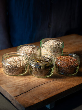Cereals grains and pumpkin seeds portioned in glasses on rustic wooden board for a bread preparation. Healthy groceries background.