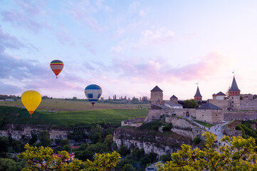 Beautiful sunset summer landscape with ancient castle and balloons in the sky. Kamianets-podilskyi, Ukraine.