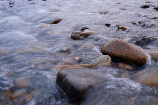 Wet stones pebbles in the mountain river flow.