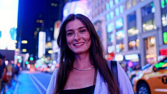 Portrait of Caucasian good-looking woman on Times Square in the USA. Pretty beautiful girl looking at camera smiling having fun. Busy streets of America with lots of people on background.