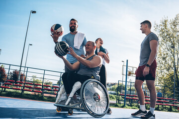 Portrait of a physically challenged man in a wheelchair with his friends on a basketball court.