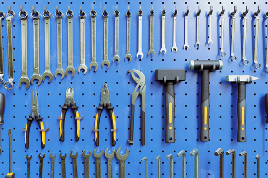 Garage tools hanging on the organizer wall. Wrenches, pliers, screwdrivers
