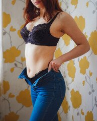 beautiful young woman in lingerie puts on jeans