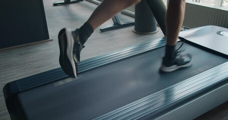 Male feet in sneakers running on treadmill at gym, closeup. Cropped view on man doing sports exercise and jogging on running machine. Cardio workout concept - Powered by Adobe