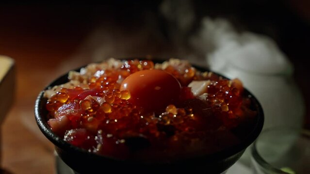 a luxurious Japanese sashimi rice dish emerges, surrounded by swirling smoke from dry ice. The misty ambiance elevates the presentation, raw egg york promising a sensory . High quality 4k footage