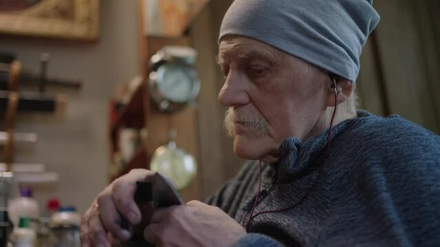 Senior gray haired male master in a wheelchair working at his workshop sharpening japanese deba knife