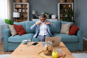 Young businesswoman sitting at home preparing for an unplanned video call with clients putting on a...
