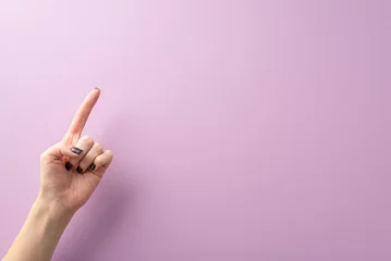 Foto op Plexiglas From first person top view, the hand of a young lady, complete with stylish black manicure, creates a pointed gesture using her index finger. The lilac background provides text or ad placement © ActionGP
