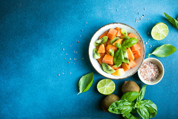 Salad with  ripe papaya fruit, kiwi lime and salt on a color background. Appetizing tropical fruit