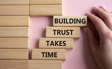 Building Trust takes Time symbol. Wooden blocks with words Building Trust takes Time. Beautiful pink background. Businessman hand. Business and Building Trust takes Time concept. Copy space.