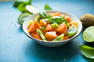 Salad with  ripe papaya fruit, kiwi lime and salt on a color background. Appetizing tropical fruit