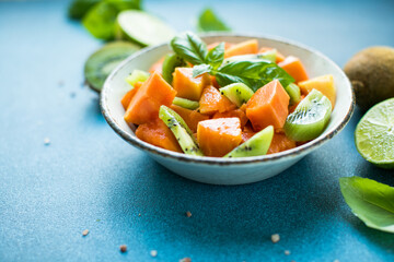 Salad with  ripe papaya fruit, kiwi lime and salt on a color background. Appetizing tropical fruit