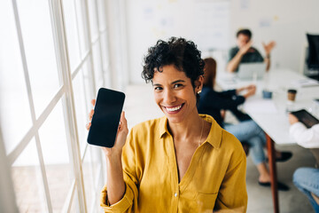 Happy business woman holding up a blank smart phone