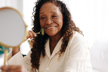 Anti-aging skincare routine: Mature woman using a jade roller on her face