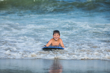 Fototapeta premium Cheerful teenage boy with a swimming board. Happy european family having fun floating on a swim board in the ocean on a hot summer day