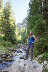 Naklejka premium Slim tourist woman standing on a big boulder against scenery mountain landscape