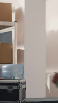 Vertical video Warehouse employee asking manager for help, unsure what to do with fragile special parcel delivery request, wanting to use hard case protective suitcase to avoid issues during shipment