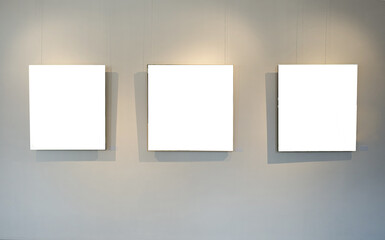 Blank picture frames on grey wall with glowing lamp, mock up