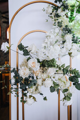 An element, part of a beautiful round wedding arch made of multi-colored flowers, stands in the restaurant. Close-up photography, portrait.