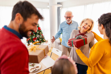 Family exchanging Christmas gifts while celebrating Christmas at home
