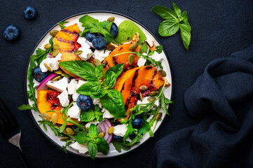Gourmet salad with grilled peaches, blueberries, red onion, feta cheese, basil and mixed herbs,...