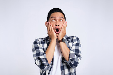 Wow, Omg. Surprised young Asian man in casual shirt looking up with open mouth and amazed facial expression isolated on white background