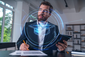 Considered businessman in formal wear signing contract holding tablet device at office room with...