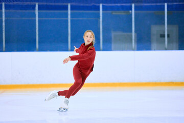 Concentrated and motivated teen girl in red sportswear training, skating on ice rink arena. Figure...